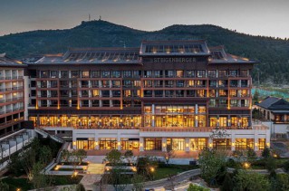 Ein eindrucksvolles Grandhotel vor einer Bergkulisse bei Sonnenuntergang.